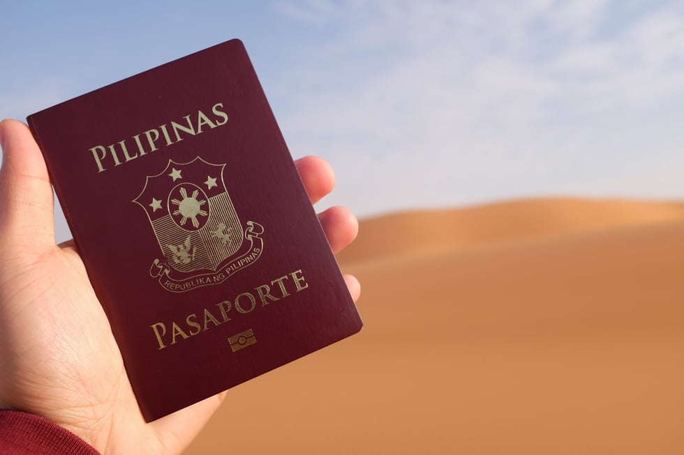 A Filipino traveler holding a Philippine passport in a desert in Riyadh, Saudi Arabia